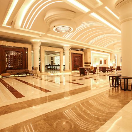 ซาวอย เลอ กร็อง โฮเต็ล มาราเกช Hotel มาร์ราเกช ภายนอก รูปภาพ The photo shows an elegant hotel lobby with a spacious and luxurious design. The floor features a mix of light and dark marble patterns, creating an appealing visual contrast. The ceiling has a modern, curved design with soft lighting that enhances t