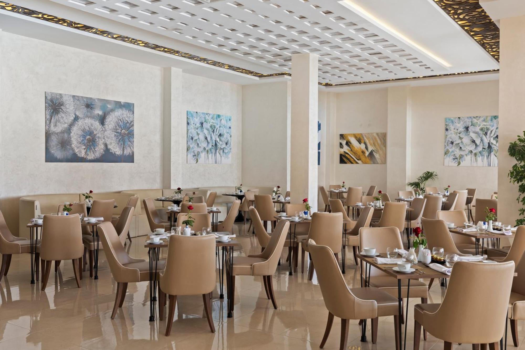 ซาวอย เลอ กร็อง โฮเต็ล มาราเกช Hotel มาร์ราเกช ภายนอก รูปภาพ The photo depicts an elegant restaurant featuring a modern and sophisticated design. The dining area includes several tables with beige chairs, creating a warm and inviting atmosphere. The walls are adorned with artistic paintings, primarily showcasi